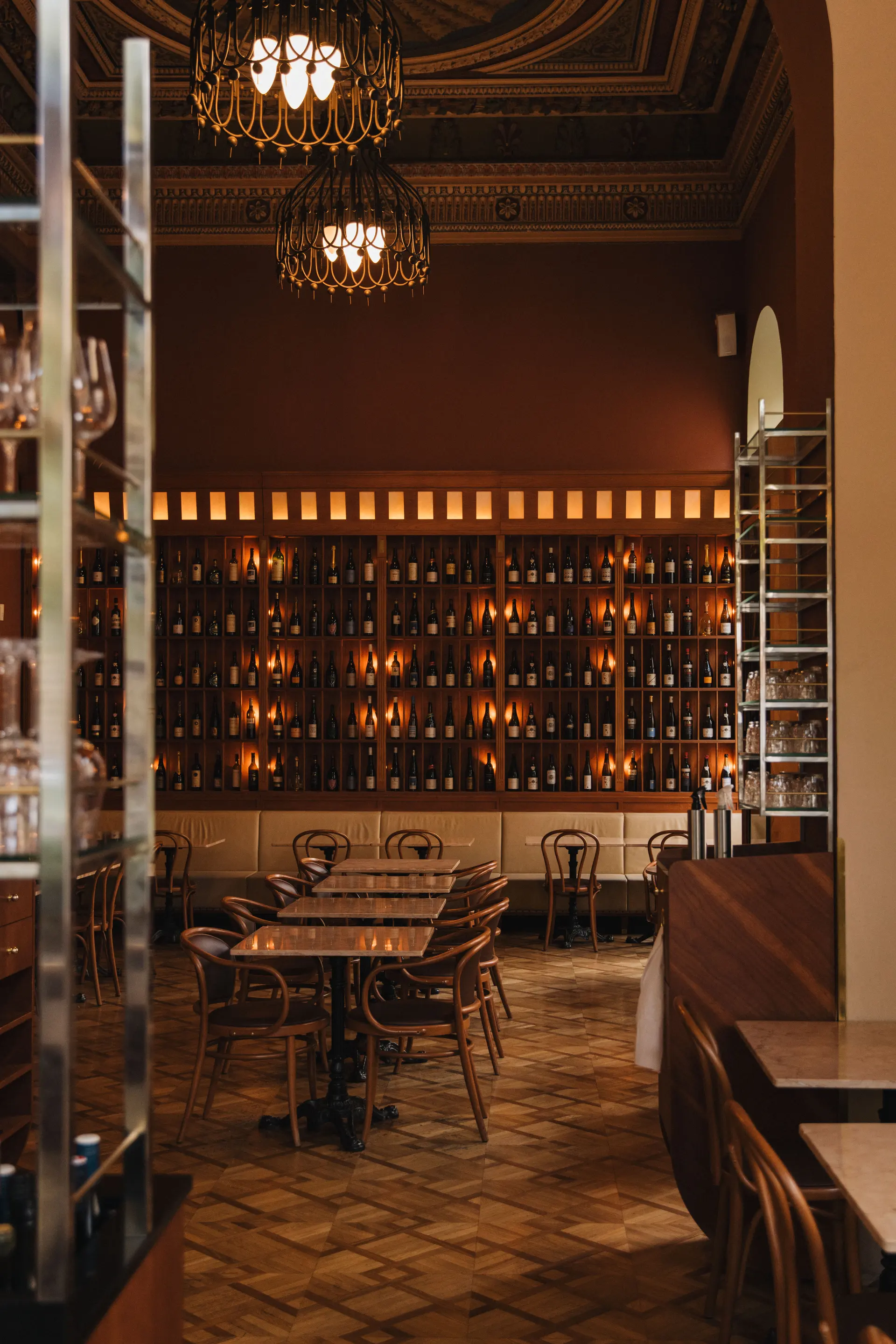 Elegant restaurant interior with wine wall, wooden tables and historic ceiling.