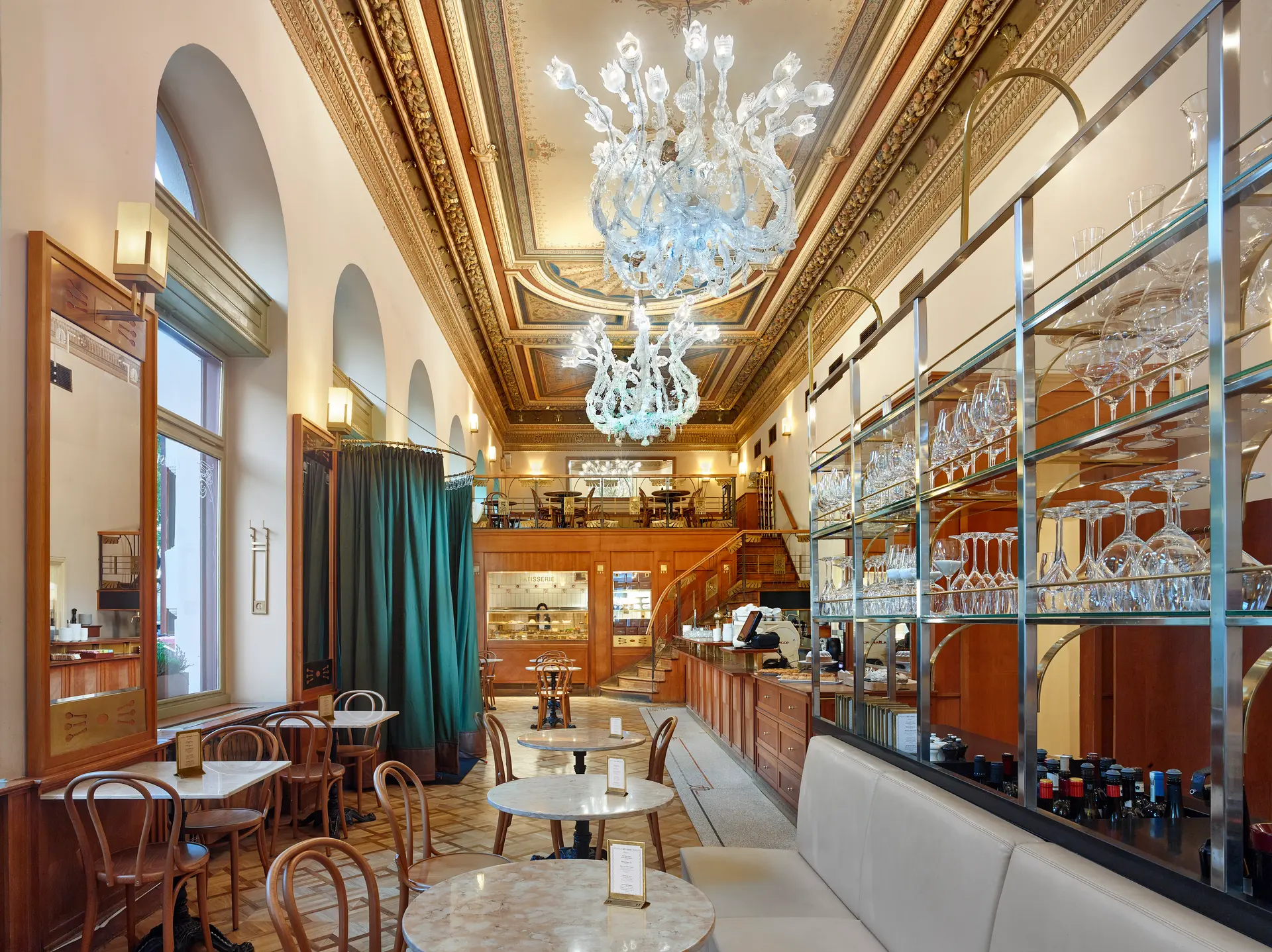 Interior of Café Savoy with chandeliers and gallery seating.